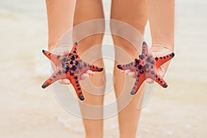 Red starfish in the hands, next to the sea