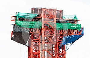 Red steel scaffolding with slan at construction site installed beside concrete pillar and beam