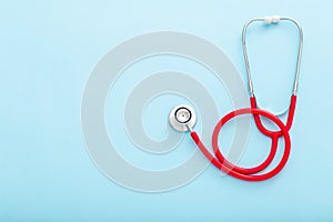 Red stethoscope on blue color background. Concept of medicine and health care. Top view copy space for text