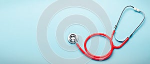 Red stethoscope on blue color background. Concept of medicine and health care. Top view copy space for text. Long web banner