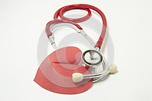 Red stethoscope chestpiece lying to red heart shape on white background vertically isolated. The idea or concept for cardiology -