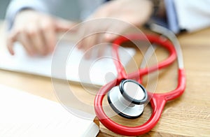 Red stethoscope is lying on table