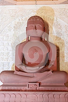  red stone jain god holy statue in meditation from different angle