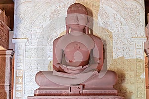  red stone jain god holy statue in meditation from different angle