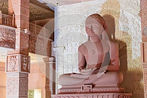  red stone jain god holy statue in meditation from different angle