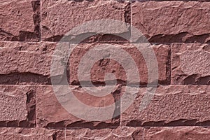Red stone wall background. The texture of the decorative stone. Close-up