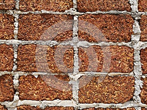 Red stone wall stacked up grout with grey cement Rock porous rough surface material texture background