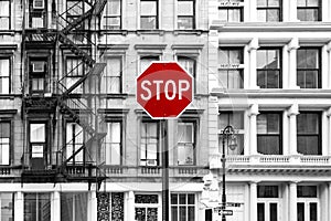 Red stop sign against background of old black and white buildings in SoHo Manhattan, New York City