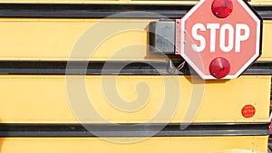 Red stop sign, yellow school bus in USA. Schoolbus or shuttle, safety on road.