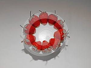 Red strawberries on white round plate studio shot