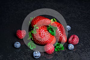 Red strawberry blueberry raspberry fresh mint on black background