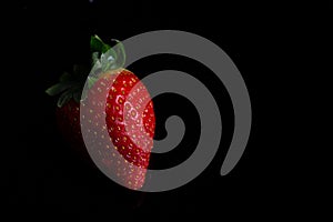 Red strawberry fruit close up skin texture on a black background