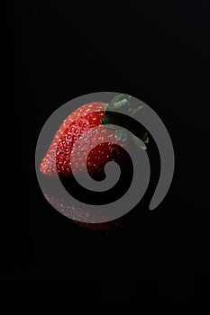 Red strawberry fruit close up skin texture on a black background