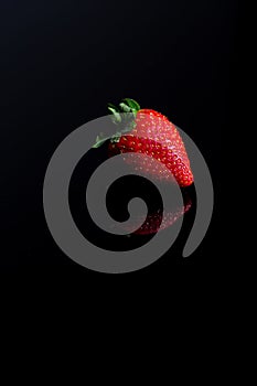 Red strawberry fruit close up skin texture on a black background