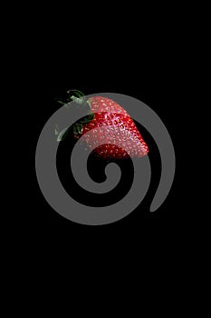 Red strawberry fruit close up skin texture on a black background