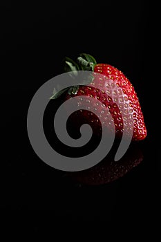 Red strawberry fruit close up skin texture on a black background