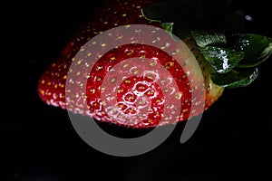 Red strawberry fruit close up skin texture on a black background