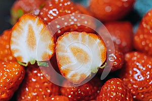 A red strawberry sliced in half, revealing its white flesh.