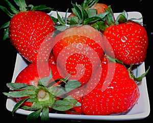 Red strawberry on a white square saucer