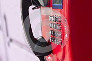 Red street payphone with round stainless steel buttons close-up.