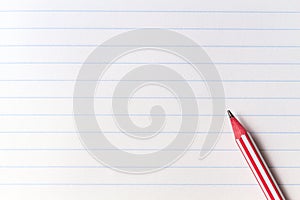 Red striped pencil on white blank notebook lined paper background with copy space. Back to school, education, learning
