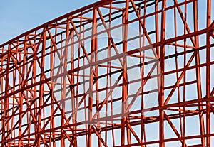 A red structure with many metal beams and a blue sky in the background