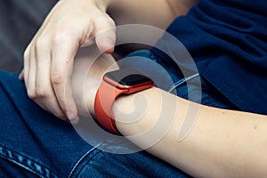 Red stylish smart watch on male wrist closeup. Touch finger on empty screen of wearable gadget to look time and data.