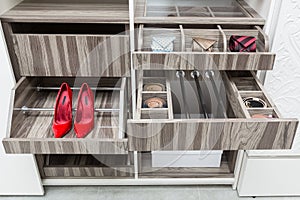 Red suede female shoes on  a shelf, storage for belts and neck ties in a wardrobe