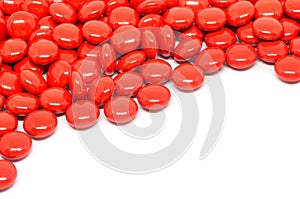 Red sugar coated pills tablets vitamin on white background