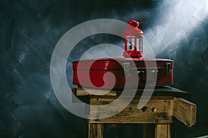 A red suitcase and a red candlestick on a dark background