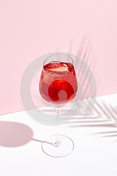 Red summer cocktail in wine glass on creative background