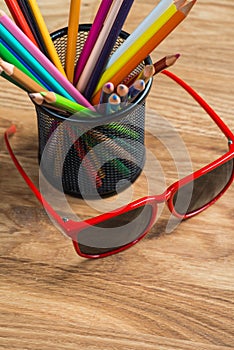 Red sun glasses with bunch of color pencils in a stand