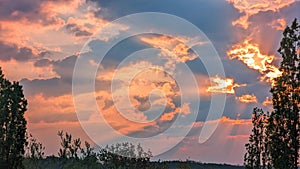 Red sun rays in the cloudy sky and glowing clouds at the sunset