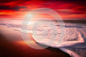 Red sunset on beach with a wave