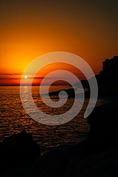 Red sunset over the sea on a rocky shore