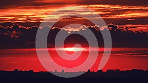 Red sunset over silhouettes of city buildings, top view