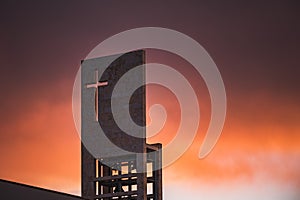 Red sunset on the sky above a modern church with christian cross