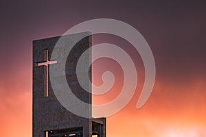Red sunset on the sky above a modern church with christian cross and copy-space
