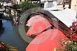 Red sunshade umbrellas along the romantic canal ,little Venice, the course of the Lauch in Colmar.