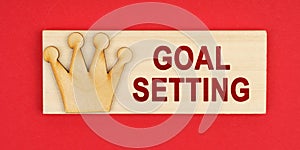 On a red surface there is a wooden block with the inscription - Goal setting