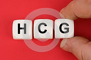 On the red surface, white cubes with the inscription - HCG