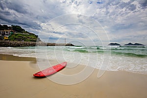 Red surfboard laying on shorebreak