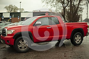 A red SUV is parked in the city. The pickup truck is on a groan