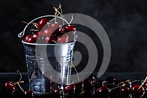 Red sweet cherries in a metal bucket on black background. Summer taste. Fresh berries