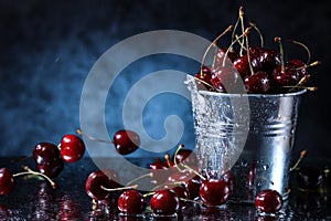 Red sweet cherries in a metal bucket on a dark and blue background. Summer taste. Fresh berries under the water drops.