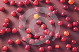 Red sweet cherry plums scattered on table.