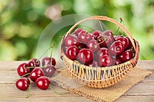 Red sweet cherry in a wicker basket on wooden table isolated on white background with clipping path and full depth of