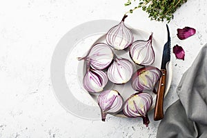 Red sweet onions halves on a white plate on a light background. Top View.