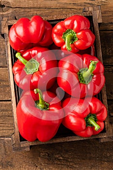 Red sweet pepper in box on old wooden background.