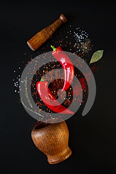 Red sweet peppers and spices on a black background.